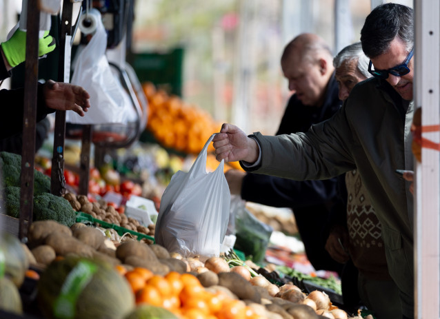Archivo - Varias personas compran en un mercado de alimentos