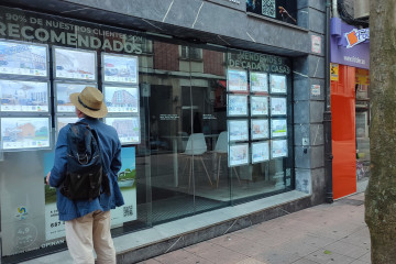 Archivo - Un hombre mira anuncios de una agencia inmobiliaria en Oviedo