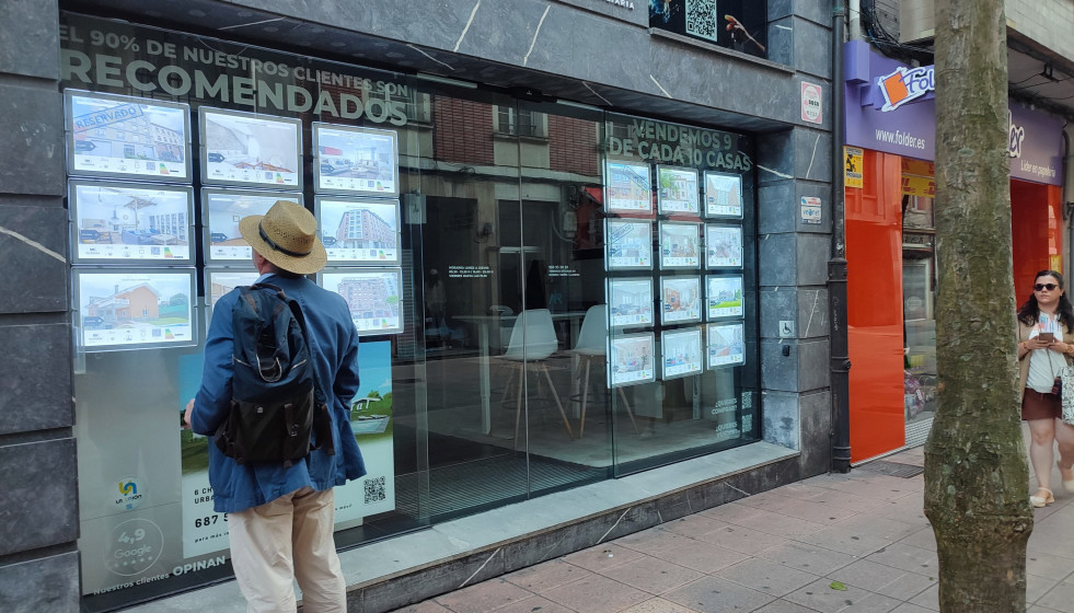 Archivo - Un hombre mira anuncios de una agencia inmobiliaria en Oviedo
