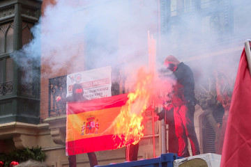 Encapuchados queman una bandera española en el centro de Bilbao al paso de una manifestación de Ernai, juventudes de Sortu, por la independencia