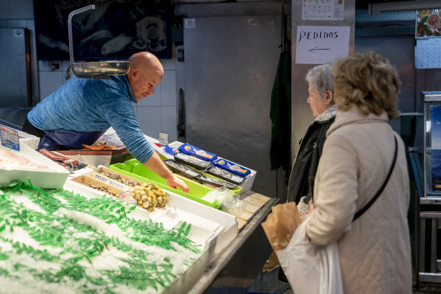 Archivo - Un trabajador autónomo atendiendo a dos clientas en su pescadería