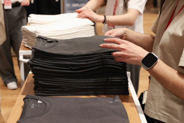 Archivo - Varios dependientes colocan la ropa en una tienda de moda