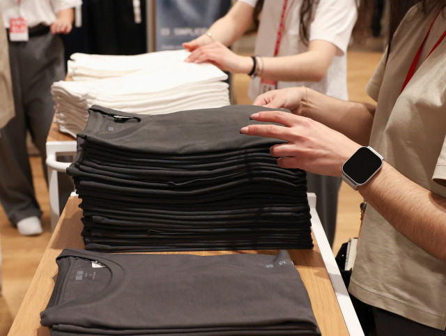 Archivo - Varios dependientes colocan la ropa en una tienda de moda