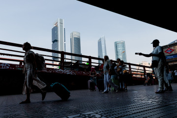 Archivo - Varias personas esperan con maletas en la estación Chamartín Clara Campoamor, con las cuatro torres de fondo, a 19 de agosto de 2025, en Madrid