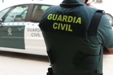 EuropaPress 4256421 agente guardia civil espaldas junto vehiculo oficial