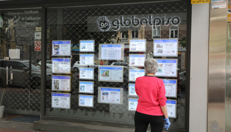 Archivo - Una mujer echa un vistazo a las ofertas de una agencia inmobiliaria.