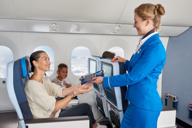 Archivo - Una azafata atiende a una pasajera y su hijo.