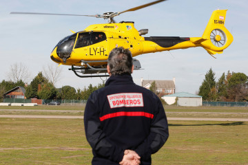 Archivo - Un miembro del efectivo de Bomberos de la Diputación de Valladolid observa un helicóptero de la Junta de Castilla y León que participa en la búsqueda de un ultraligero y a las dos person