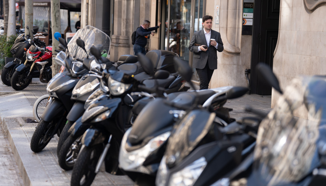 Archivo - Varias personas caminan al lado de motos