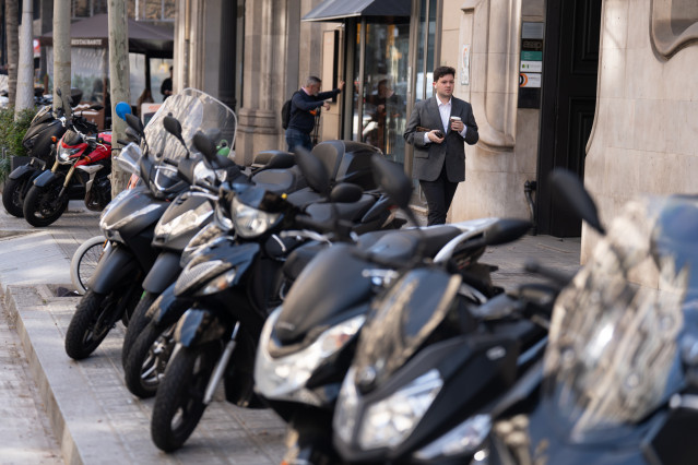 Archivo - Varias personas caminan al lado de motos