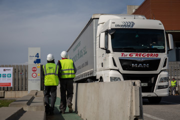 Archivo - Dos trabajadores junto a un camión en Barcelona.
