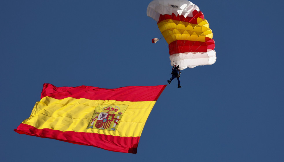Archivo - La bandera de España con uno de los miembros de la patrulla paracaídista del Ejército del Aire, durante el acto solemne de homenaje a la bandera nacional y desfile militar en el Día de l