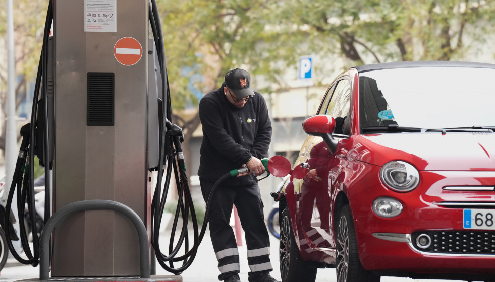 Un hombre echando combustible a su vehículo en una gasolinera
