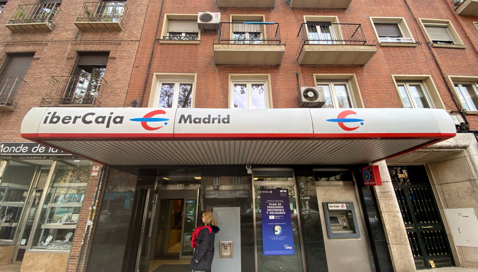 Archivo - Una mujer entra en un una oficina de IberCaja en Madrid.