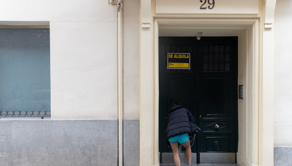 Archivo - Una persona pasa a un edificio donde hay un cartel de ‘Se alquila'.