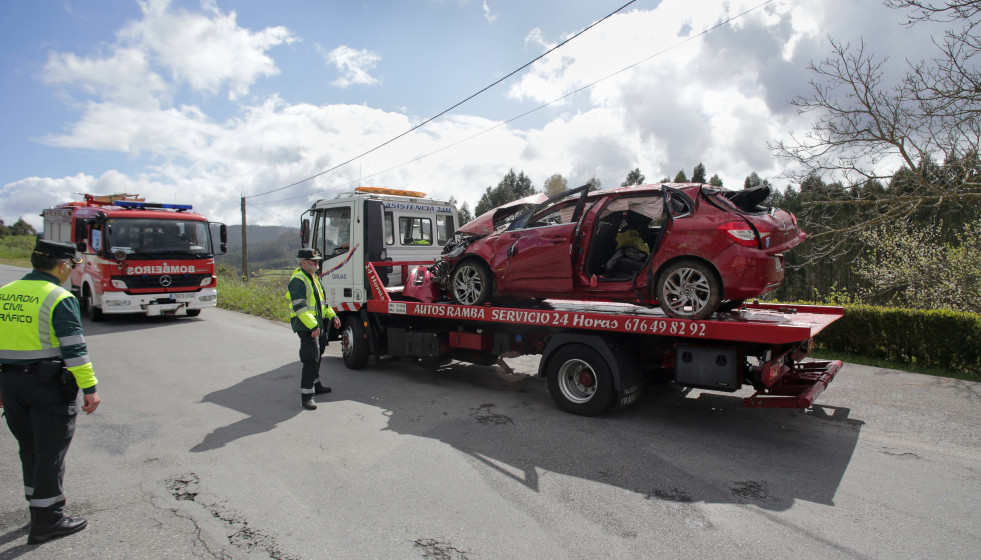 Archivo - Efectivos de Guardia Civil vigilan la retirada del coche siniestrado por una grúa.