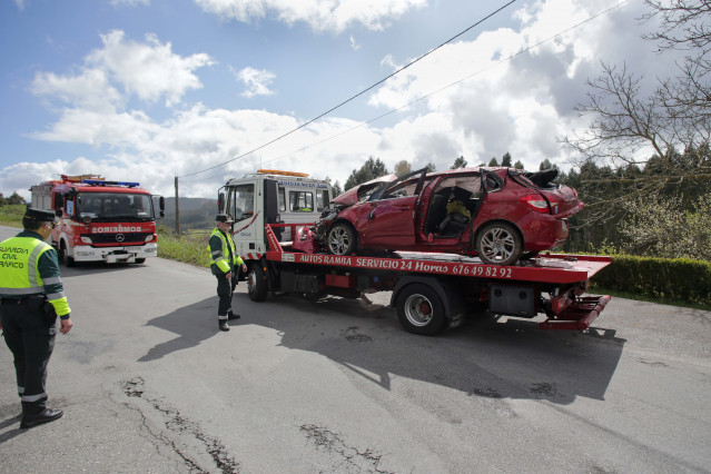 Archivo - Efectivos de Guardia Civil vigilan la retirada del coche siniestrado por una grúa.