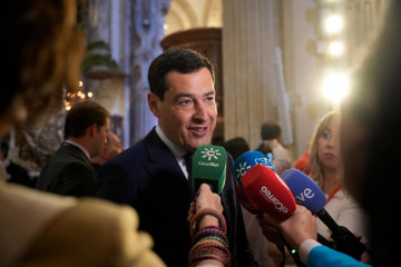 El presidente de la Junta de Andalucía, Juanma Moreno, atiende a los medios antes de la salida de La Borriquita en la iglesia de El Salvador de Sevilla.