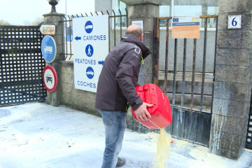 Manifestantes rocían con bidones de leche la puerta de entrada de la Fábrica Leche Celta.