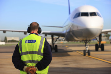 Archivo - Trabajador de la compañía John Menzies junto con uno de sus aviones.