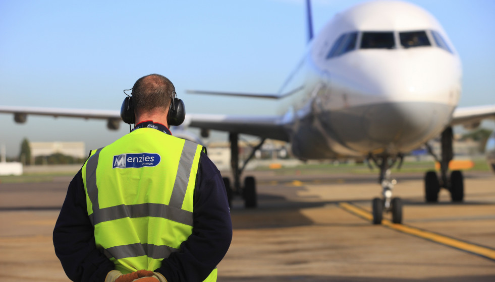 Archivo - Trabajador de la compañía John Menzies junto con uno de sus aviones.