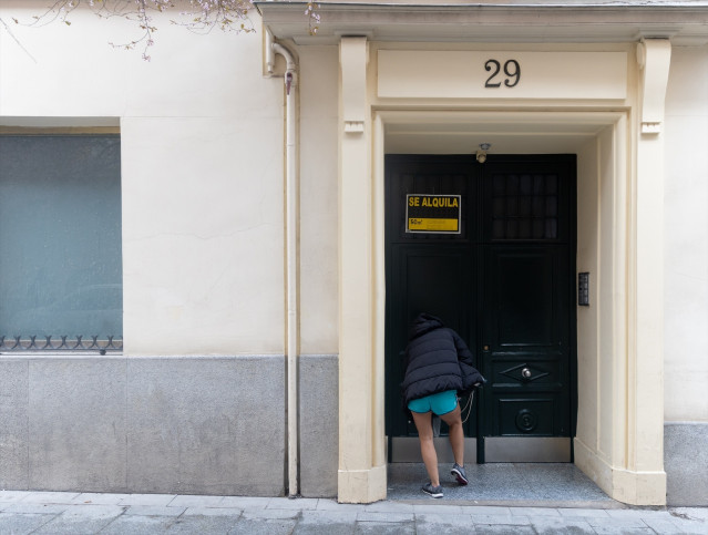Archivo - (Foto de ARCHIVO) Una persona pasa a un edificio donde hay un cartel de ‘Se alquila’