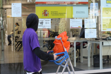 Archivo - Un joven pasa con una carretilla por una oficina de empleo de Madrid