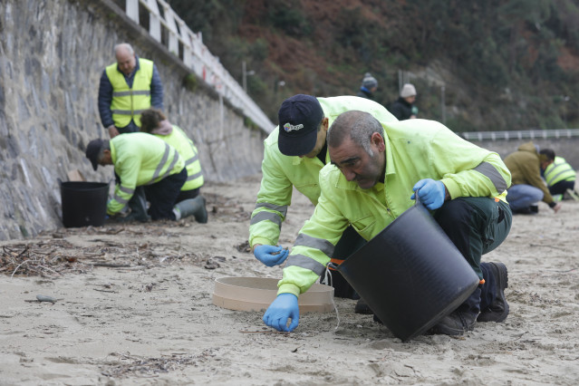 Archivo - Operarios de TRAGSA recogen pellets de plástico, en la playa de Aguilar