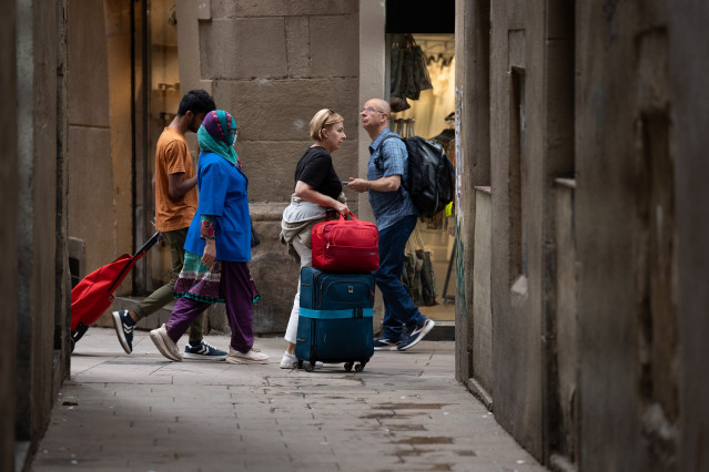 Archivo - Varios turistas con maletas en el centro de Barcelona