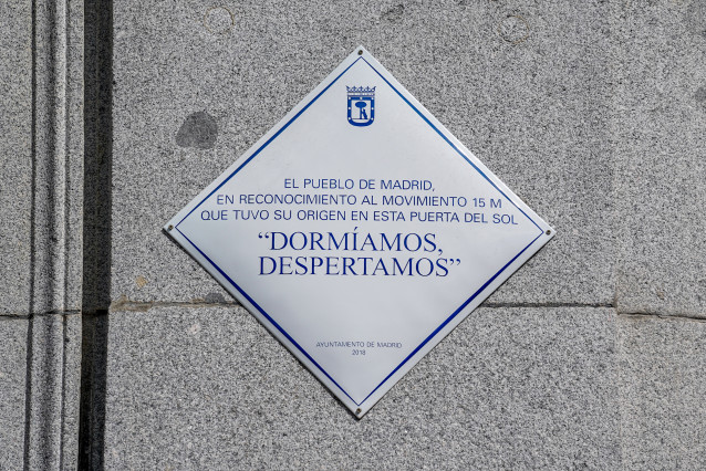Archivo - Placa con uno de los lemas ya clásicos del 15M, 'Dormíamos, despertamos', que luce en el número 10 de la Puerta del Sol desde hace dos años y medio, a 12 de mayo de 2021, en Madrid (España). La placa se encuentra a metros del punto donde estuvo