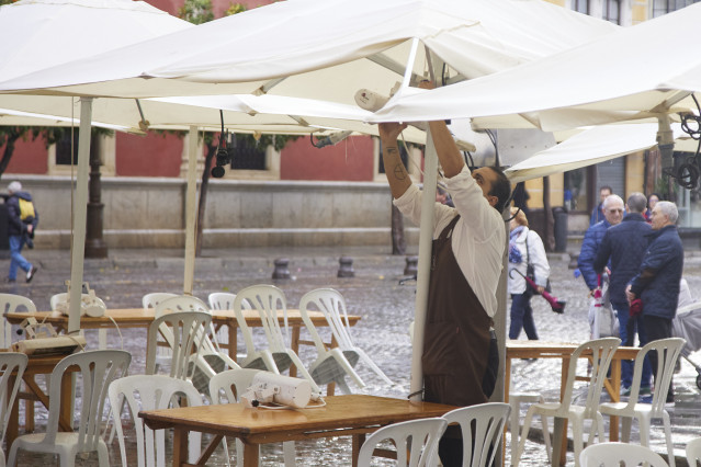 Archivo - Un camarero preparando la terraza para los clientes de un bar