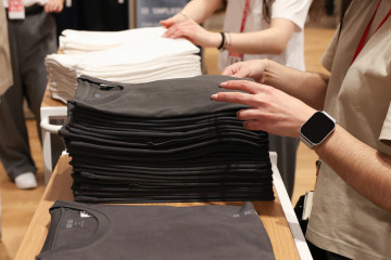 Archivo - Varios dependientes colocan la ropa en una tienda de moda.