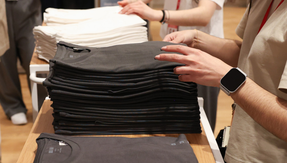 Archivo - Varios dependientes colocan la ropa en una tienda de moda.