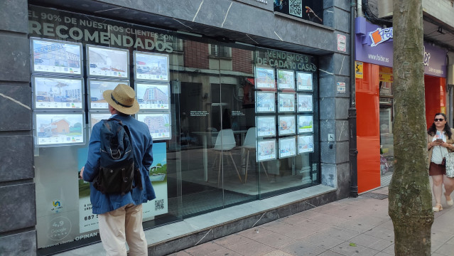 Archivo - Un hombre mira anuncios de una agencia inmobiliaria en Oviedo