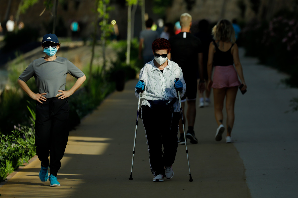 Varios adultos pasean y hacen ejercicio con mascarillas junto al río Segura, en Murcia (España), a 2 de mayo de 2020.