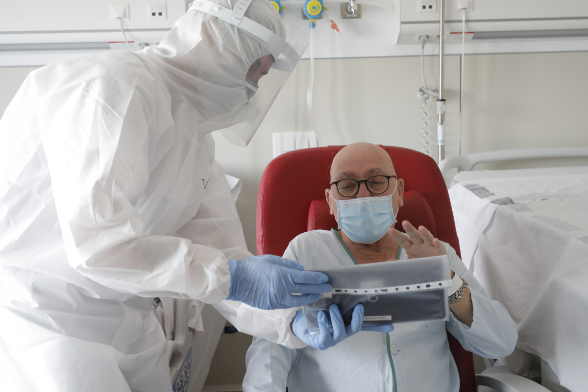Un trabajador sanitario ayuda a hacer una videoconferencia en la habitación de un paciente negativo de Covid-19 en el Hospital Arnau de Vilanova en imagen de archivo