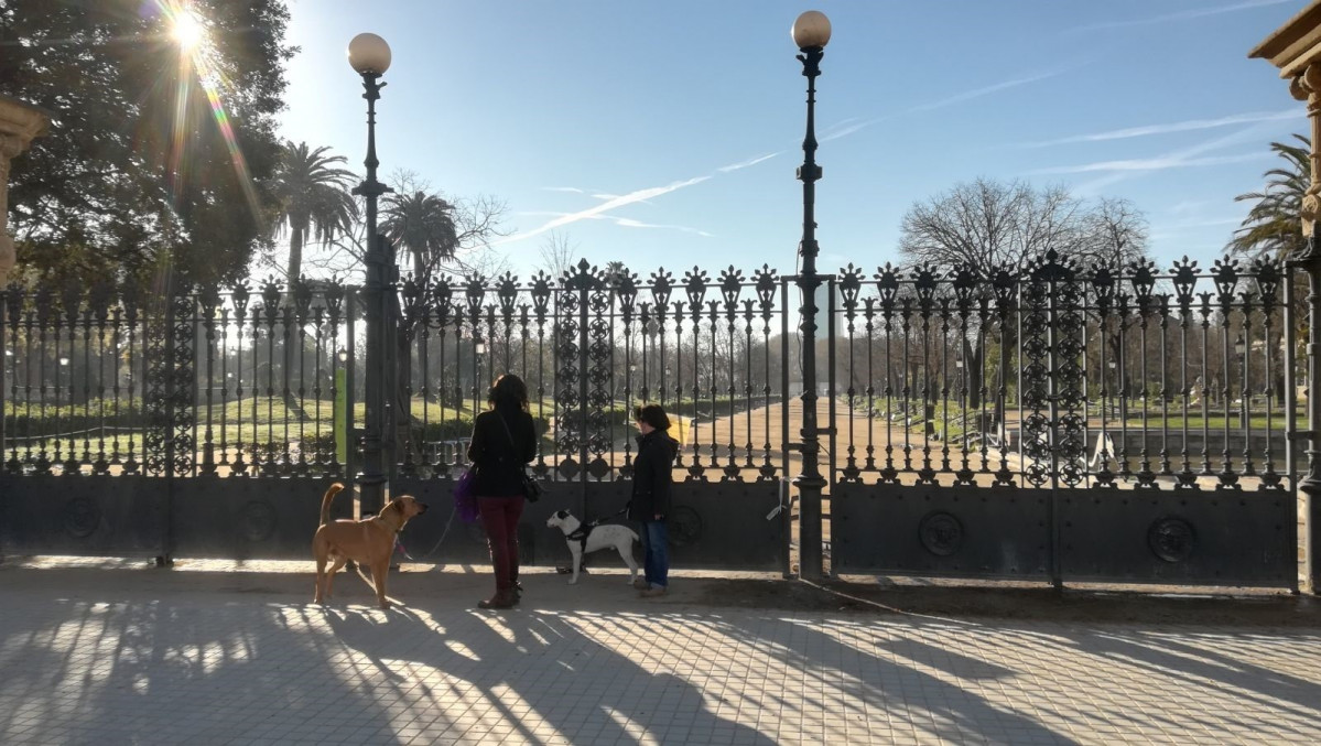 Dos mujeres pasean a sus perros por la entrada del Parc de la Ciutadella de Barcelona, cerrado