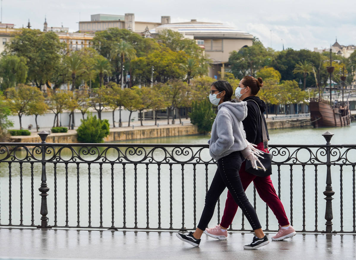 EuropaPress 2721882 dos jovenes mascarillas paseando andando puente triana tercer dia alarma