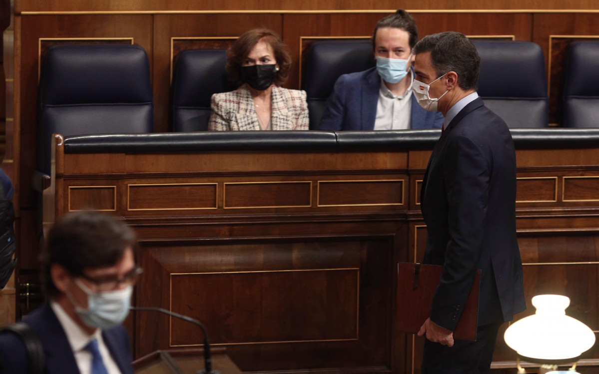 El presidente del Gobierno, Pedro Sánchez, pasa por delante la vicepresidenta primera del Gobierno, Carmen Calvo, y el vicepresidente segundo del Gobierno, Pablo Iglesias, durante una sesión de control al Gobierno en el Congreso