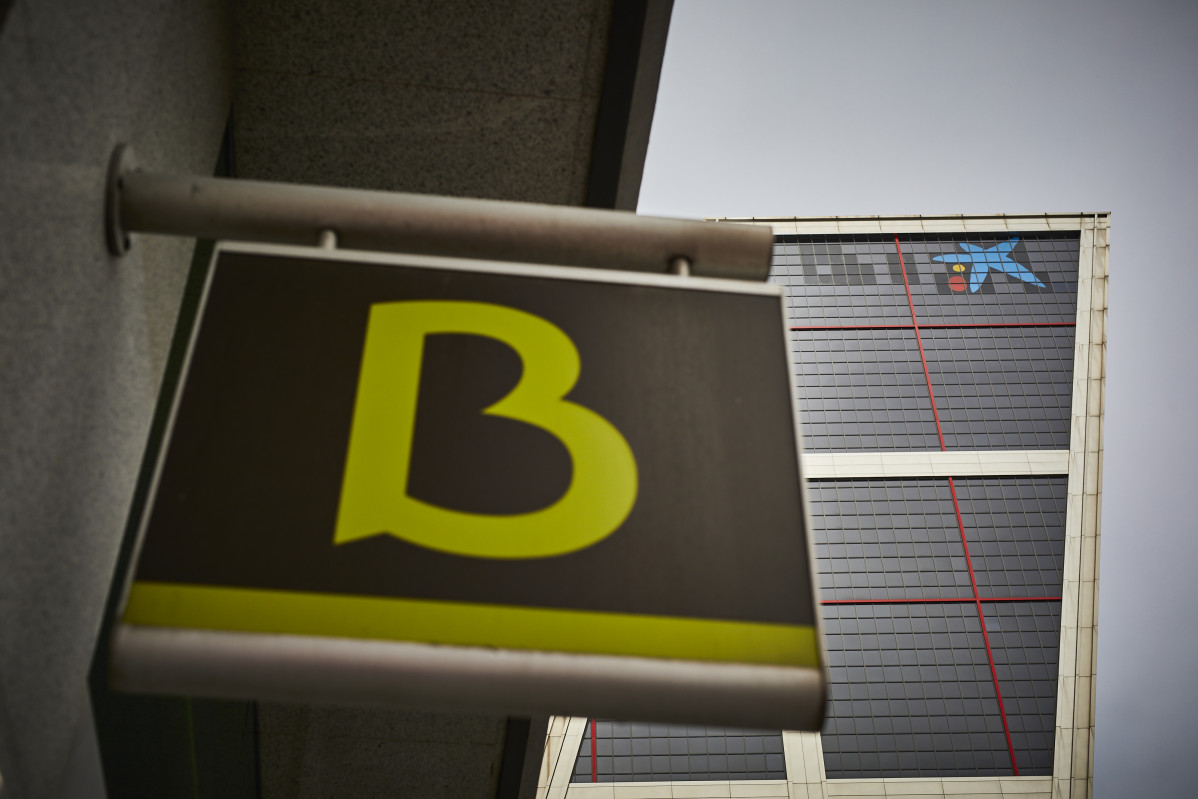 Un cartel con el símbolo de Bankia delante del logo de Caixabank.