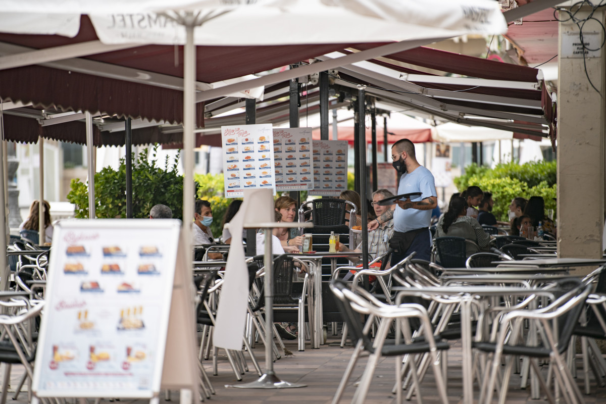 Archivo - Un camarero atiende una mesa en la terraza de una cafetería