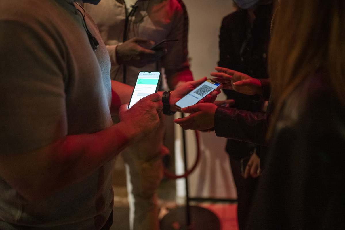 Una persona muestra un código QR para entrar a un local de ocio nocturno la misma noche en que entra en vigor la reapertura en interiores a medianoche, a 8 de octubre de 2021, en Barcelona, Cataluña (España).