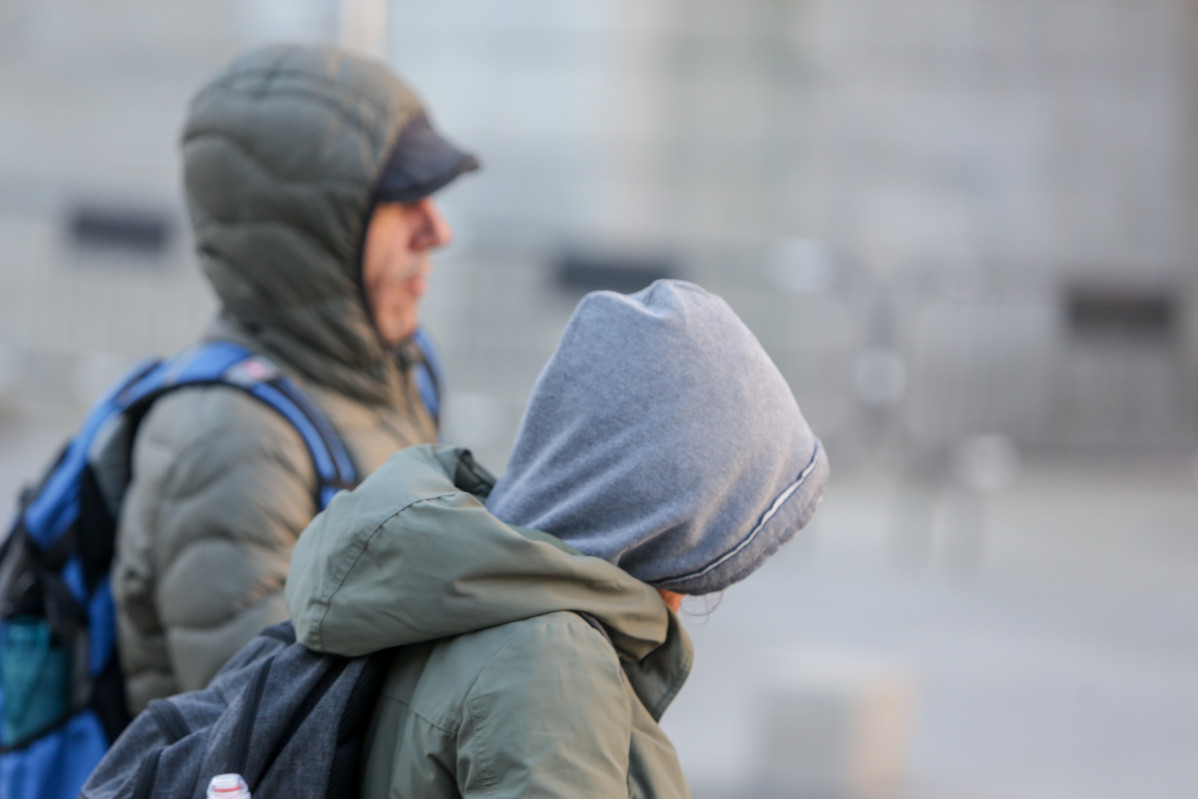 Archivo - Arxiu - Dos jovenes es protegeixen del fred amb abrics i capells mentre passegen durant un dia de vent