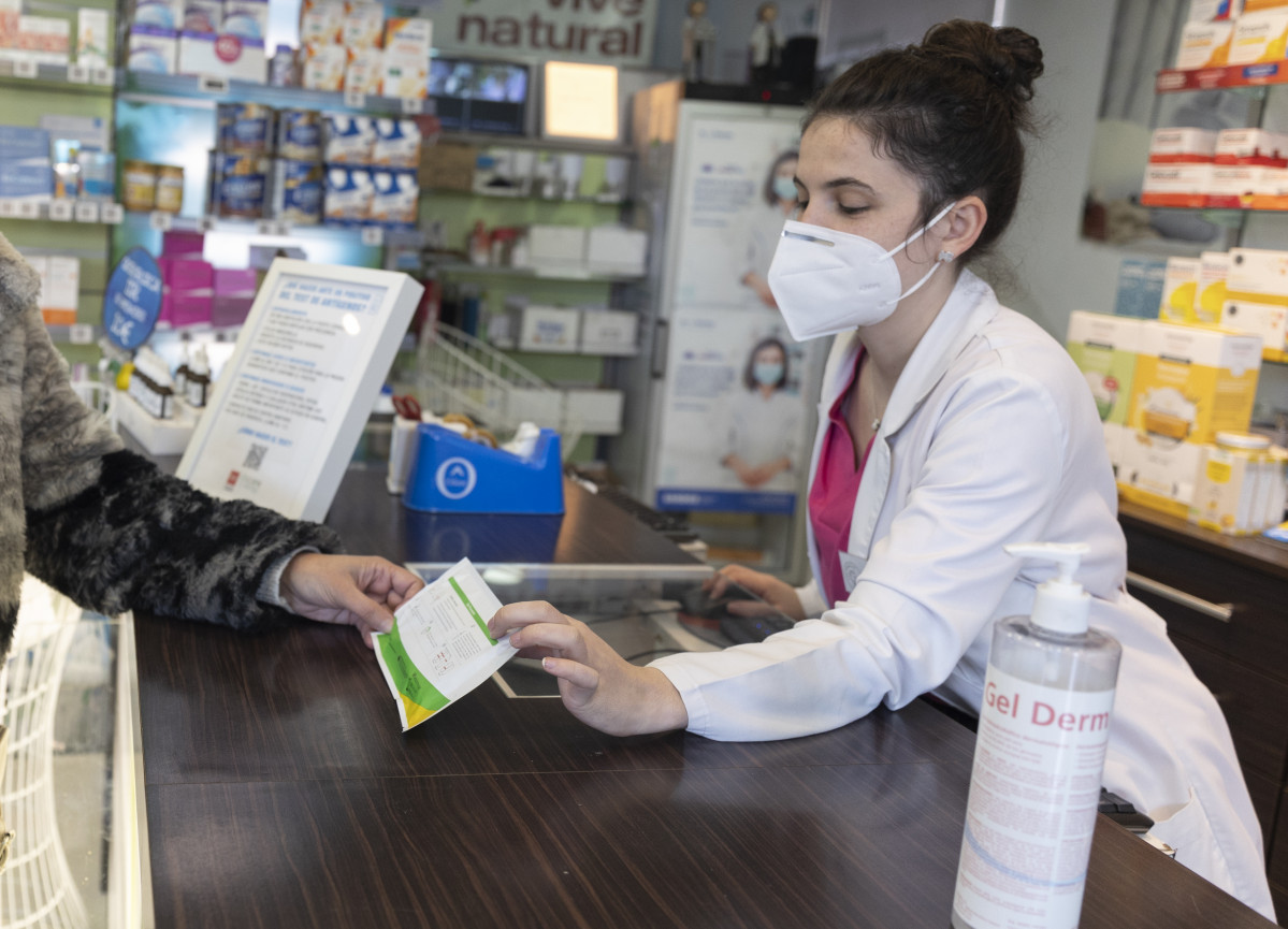 Una farmacéutica muestra un test de antígenos a una persona en la farmacia ‘Las Gemelas’, a 10 de enero de 2022, en Madrid (España). El presidente del Gobierno, ha anunciado que el Gobierno tiene previsto controlar los precios de los test de antígenos y q